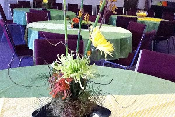 event centerpiece of orange Protea, green and yellow Spider mums, orange Kangaroo paw, Horsetail, and curly willow