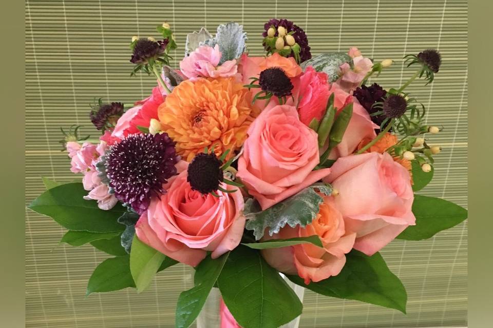 Bohemian style hand tied bouquet in coral tones with a deep highlight of Midnight Scabiosa.  Roses, Hypericum, Alaskan Grown Dahlias and more.