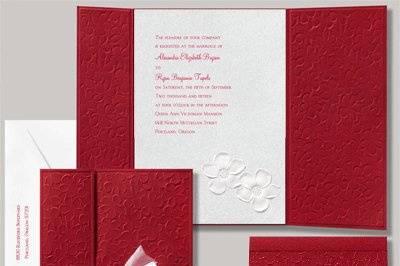Apple Blossom Invitation - Snow White - This wedding invitation is cloaked in bright red paper embossed with apple blossoms inspired by the romantic legend of Snow White. The white shimmer invitation card inside are accented with foil embossed apple blossoms and are printed with your wording in your choice of ink color and up to two lettering styles. Sheer white ribbon is included for tying around the wrap. Assembly is required. Bright white inner and outer envelopes are included. 5 1/2