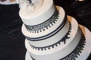 A beautiful ivory buttercream cake with black fondant ribbon, and lovely black fondant bow and hand-piped lace detail.