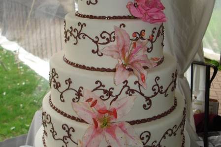 Hand-made and hand-painted sugar star gazer lilies add a special touch to this four-tiered fondant cake with chocolate scrolls