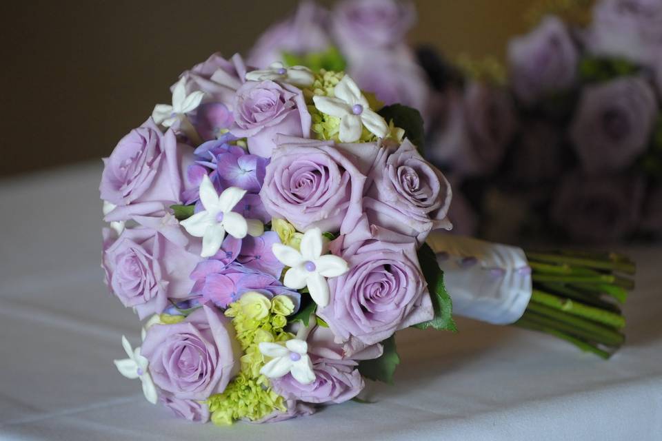 Hand tied bouquet of lavender roses, green hydrangea, and stephanotis.