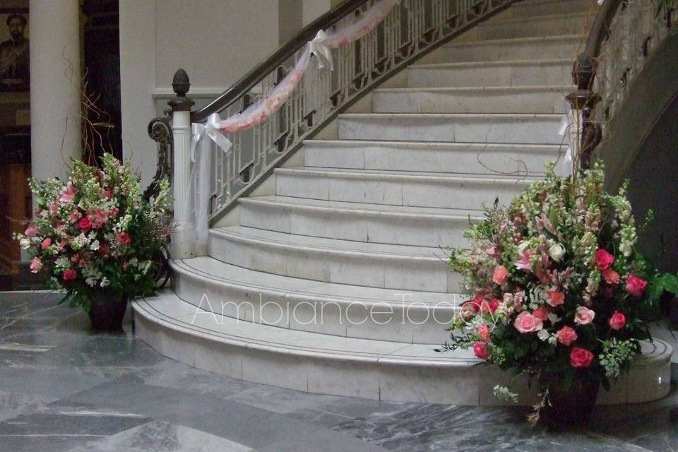 Two classically shaped 3arrangements of pink #roses, #lilies, #snapdragons, #queen anne's lace, #carnations, #calcynia, #larkspur and greens flank the bottom of the formal staircase where the ceremony is to take place.  #Tulle #wags filled with fresh rose petals line the staircase from which the bride will descend.