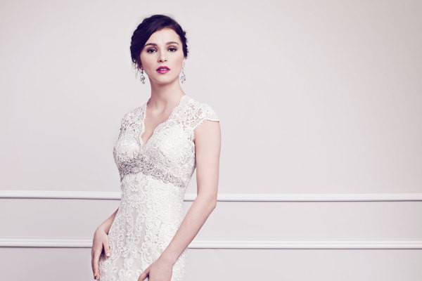 Kenneth Winston 1584- Classic V-neckline gown wrapped with floral arrangements made of Venice Lace creating a bold contrast finished with heavily beaded arch of jewels and crystals. Zipper back.