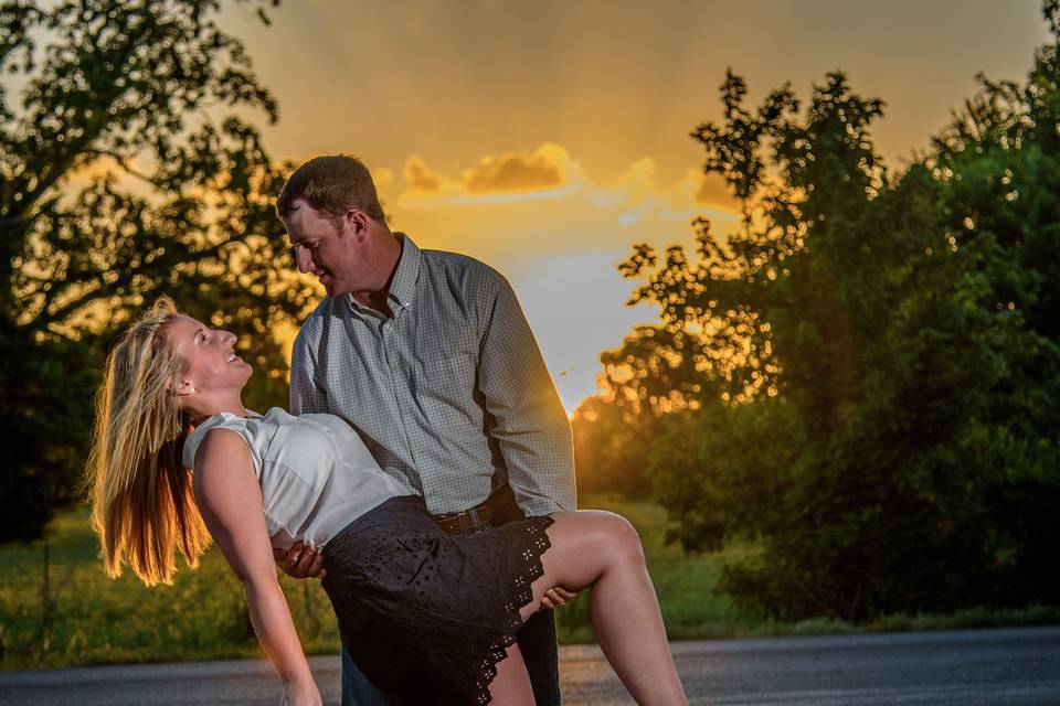 country engagement shoot with groom dipping bride in front of sunset