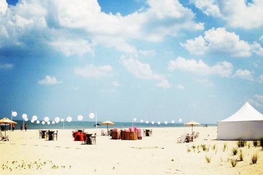 Beach Ceremony with 2 cocktail tables and white wedding arch