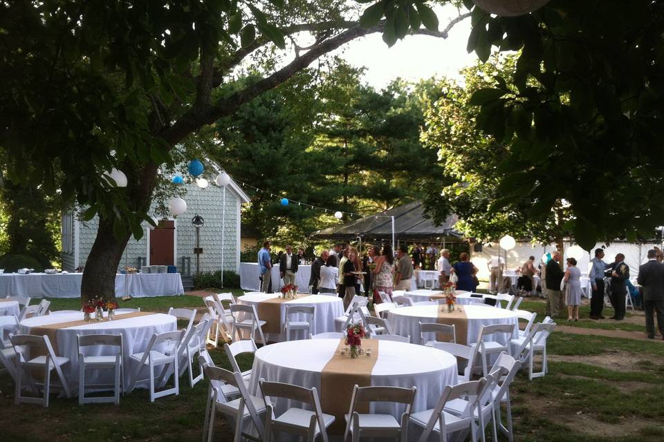 Outdoor wedding reception with white linens, burlap runners and white resin folding chairs