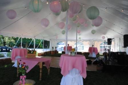 Tented wedding reception with draping California lighting, linen covered tables and white plastic folding chairs