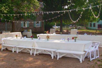 Outdoor wedding reception with white linens, burlap runners and white resin folding chairs