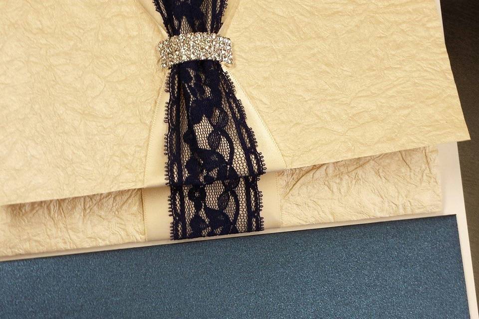 Beautiful tri-fold ivory crinkle handmade paper and lace with a curved rhinestone buckle