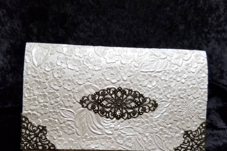 Brass corner embellishments and unique brass center piece on an ivory embossed floral paper.