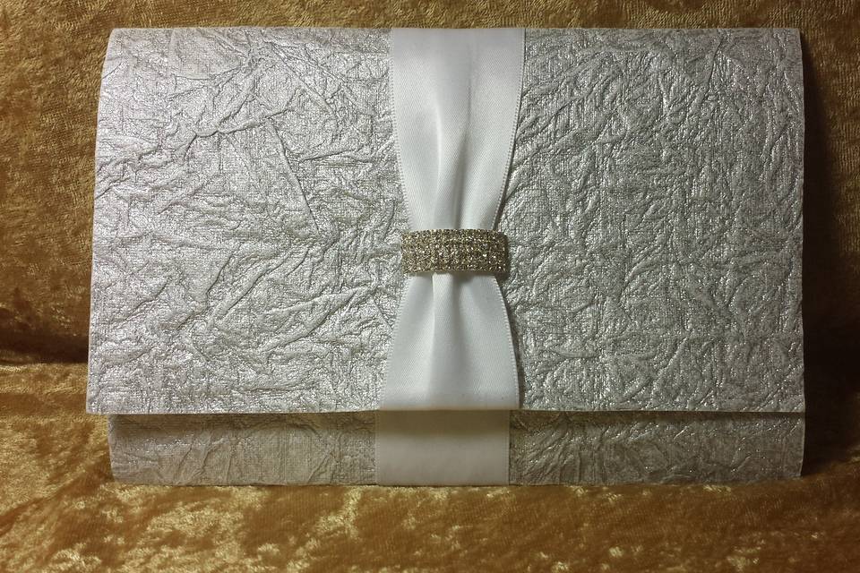 This silver crinkled paper from India with satin ribbon and large curved buckle is a tri-fold with a pocket to enfold the enclosure cards