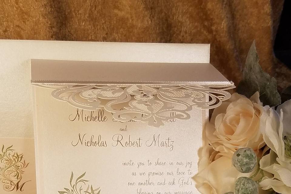 Long tri-fold shimmery laser cut invitation with brown and green floral motif.