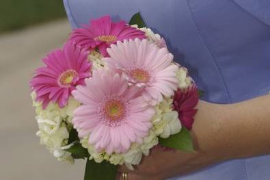Two shades of pink gerbera daisies with white hydrangea and greens.