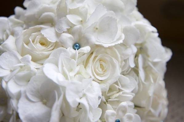 All white bouquet of roses, hydrangea, and stephanotis accented with tiffany blue pearls.