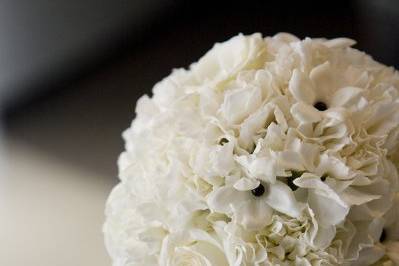 All white cake topper of roses, carnations, and stephanotis with black pearls.