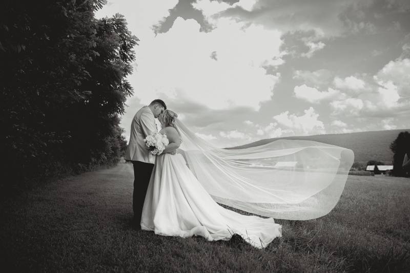 Couple kisses with sky backdrp