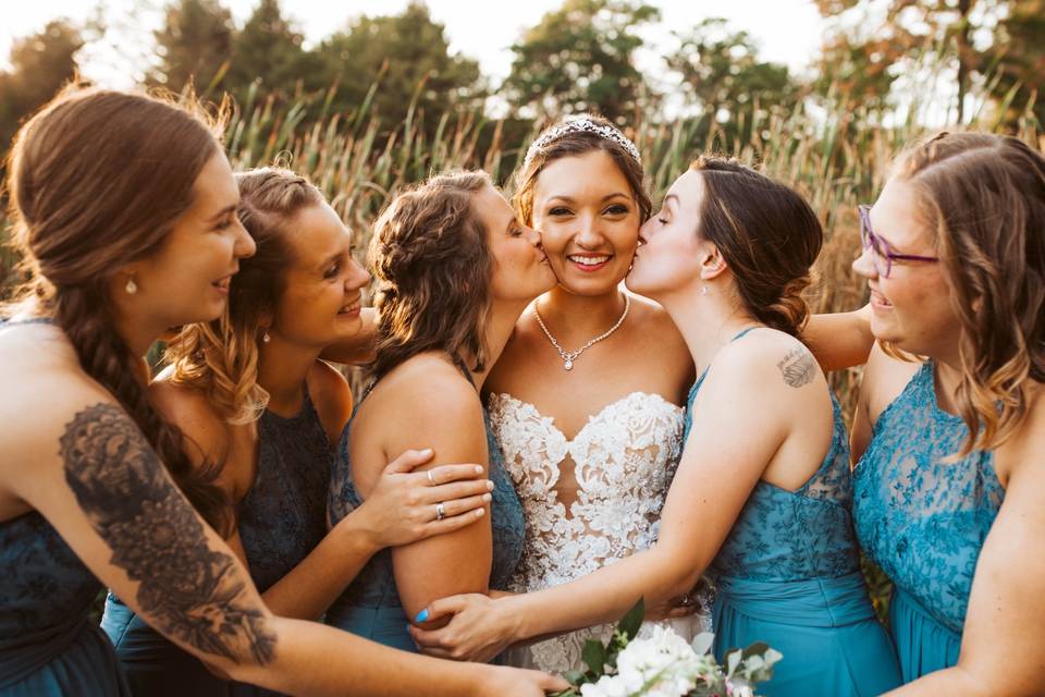 Wedding party kisses bride on cheeks