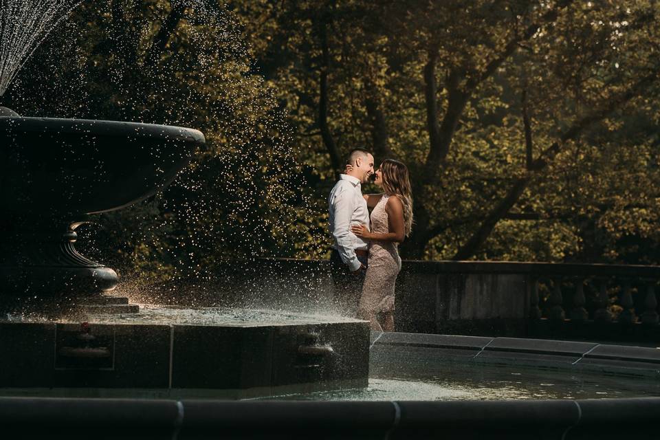 Engaged couple by a fountain
