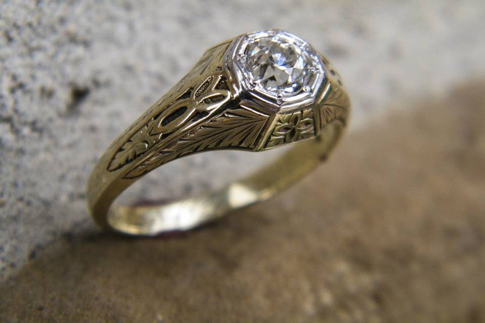 An estate yellow and white gold diamond ring with an intricate engraved design.