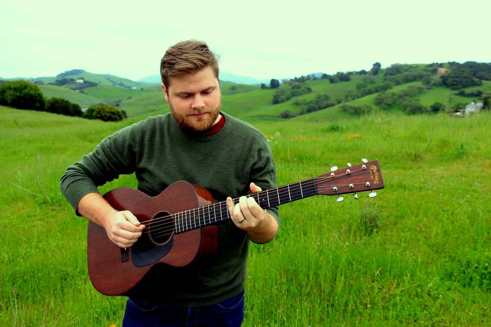 Playing guitar on a green hill