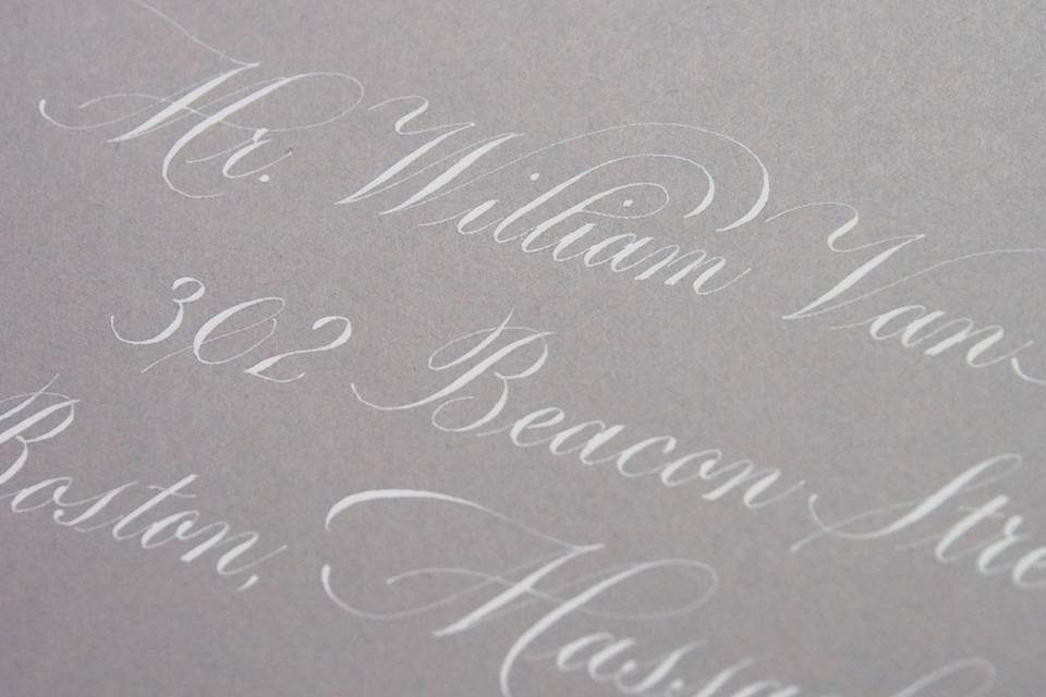White ink in a Copperplate script on a grey envelope