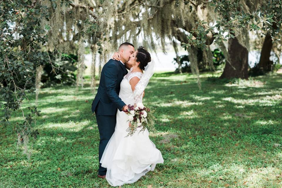 Newlyweds kiss by the oak trees