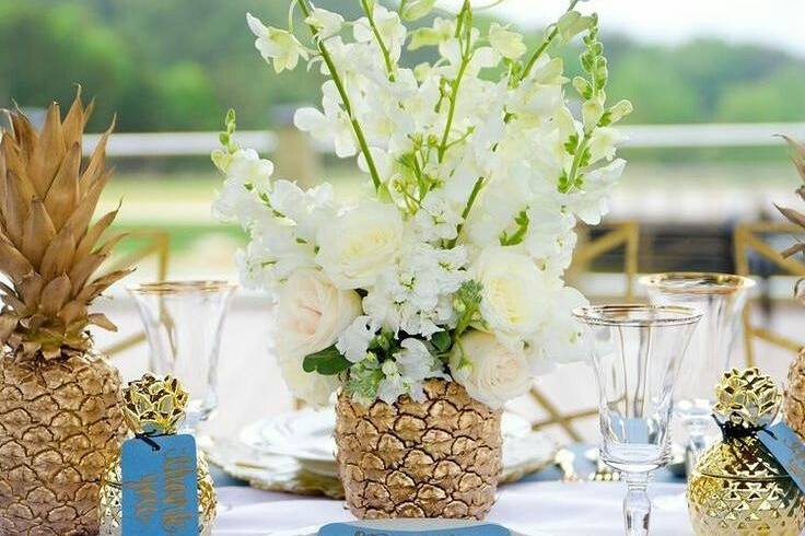 Pineapple centerpiece with fresh orchids and roses.