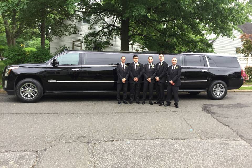 The perfect bridal party poses with our 12-passenger Cadillac Escalade.