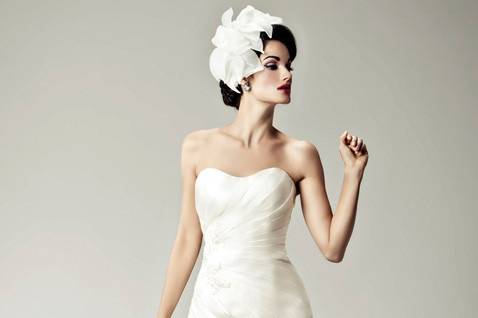 Spellbound:
All eyes will be on you in this stunning silk shantung gown.  Asymmetrical seaming wraps from the sweetheart neckline to the trumpet skirt, finished in a modified chapel-length train.  Beautiful beading and feathers accent the narrowest part of your waist. White and off-white