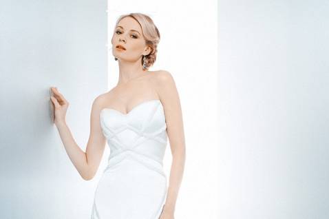 Donna Reed:
Fresh and light, floral embroidery and silk chiffon bias bands float from the bateau neckline on a sheer tulle overlay over a beautiful strapless gown. The full tulle ballgown swells to a modified chapel-length train. White and off-white