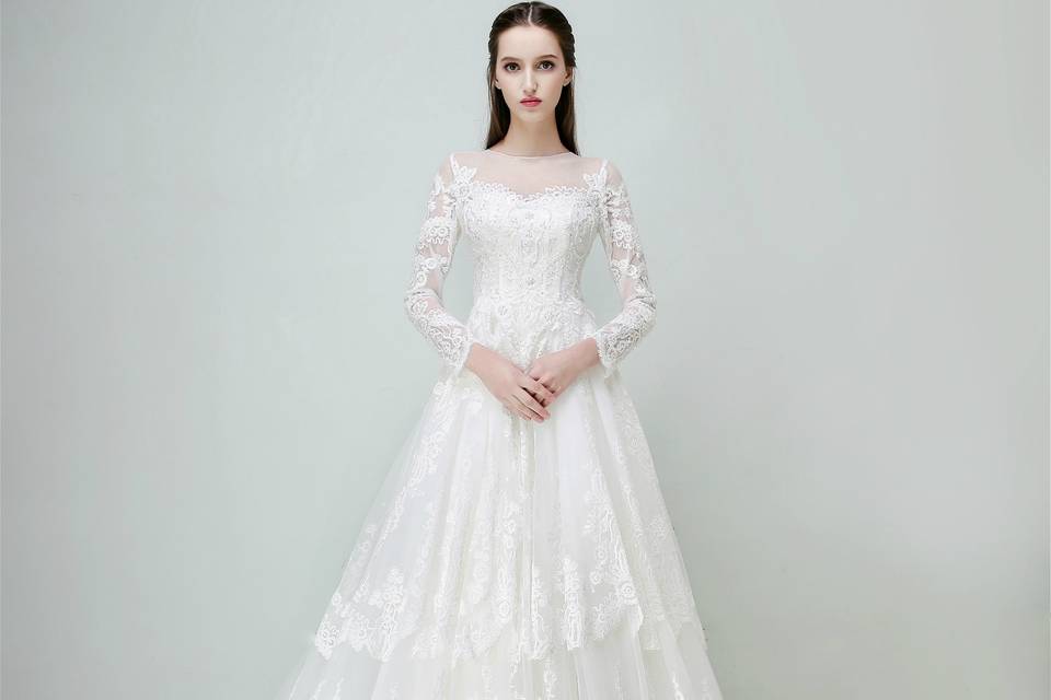 Fully-embroidered with elegant French lace appliques and hem lace beaded with iridescent sequins and pearls, this long-sleeve off-shoulder dress offers a touch of princess-like elegance and edginess. Its flutters of sheer fabric and flattering streamlined A-line silhouettes make the bride who owns it speak out their inner goddess or muse. The carefully arranged large lace paneling along the multi layered tulle train across the whole dress evokes the soul of effortless and flirty feminine glamor.