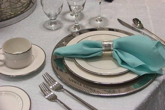 Silver band plates, silverplate charger, quantum flatware, and aqua and white linens.