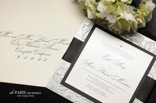 The Paris Embossed Wedding Invitation with silver embossed paper, crystal accent and silk ribbon from Brenna Catalano Design Studio. Ribbon and accent colors can be customized.