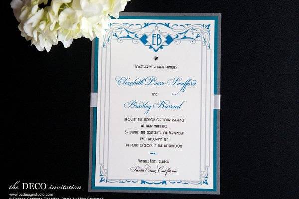 The Deco invitation with scroll design and crystal accent, initials at top and satin ribbon from Brenna Catalano Design Studio. Color can be customized.