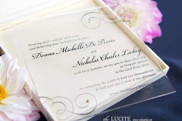 The modern Lucite wedding invitation is printed on plexiglas and accented with Swarovski crystals. Comes in an envelope but can be upgraded to a silk box. Design is customizable.