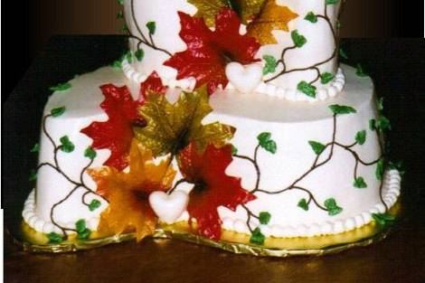 SWEET AUTUMN DREAMS:  2-tier coma shaped with simple vines and leaves of frosting accented with silk fall leaves and deco hearts.