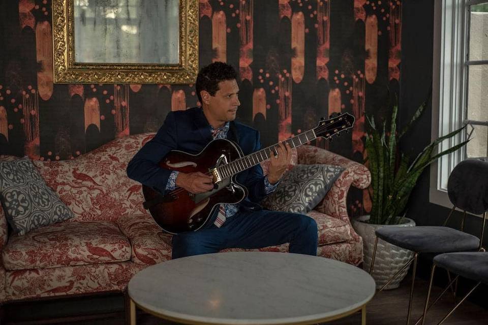 Seated on a couch with the guitar