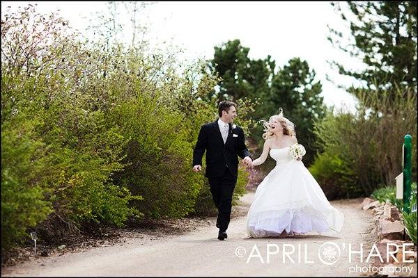 Bride & groom have some fun running down a dirt path at Hudson Gardens in Littleton, CO