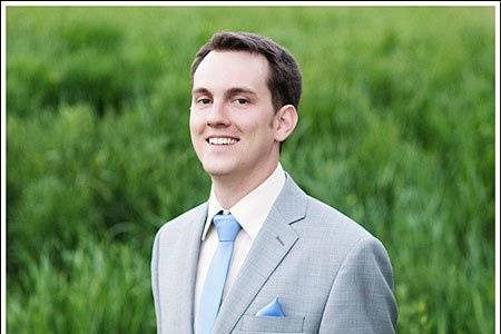 A groom wearing a blue/grey suit with periwinkle accessories at the 63rd St. Farm in Boulder, CO