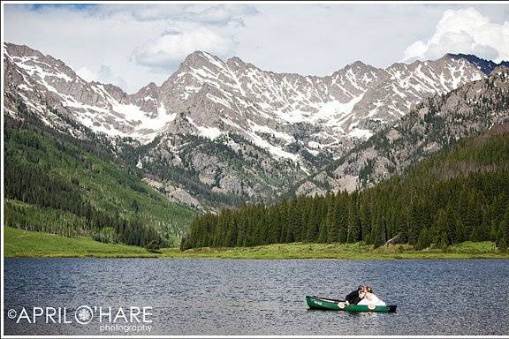 A bride & groom kiss on a canoe with a stunning view of the mountains behind them at Piney River Ranch in Vail, CO