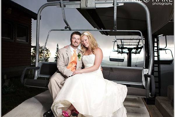 A bride & groom pose on a ski lift at their wedding in Steamboat Springs, CO