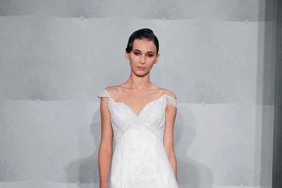 Style 32593436  This sheath gown features a tip of the shoulder neckline with an empire waist in chantilly lace and beaded embroidery. It has a chapel train and cap sleeves. This gown is Exclusive to Kleinfeld Bridal.