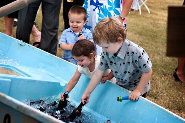 Kids at reception play with beer bottles chilled in ice in a row boat