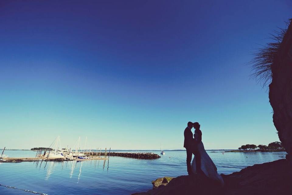 Newlyweds kissing by the water