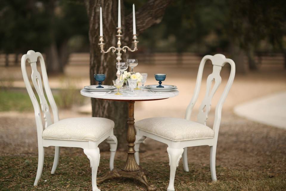 White granite sweetheart table with two shabby chic white chairs.