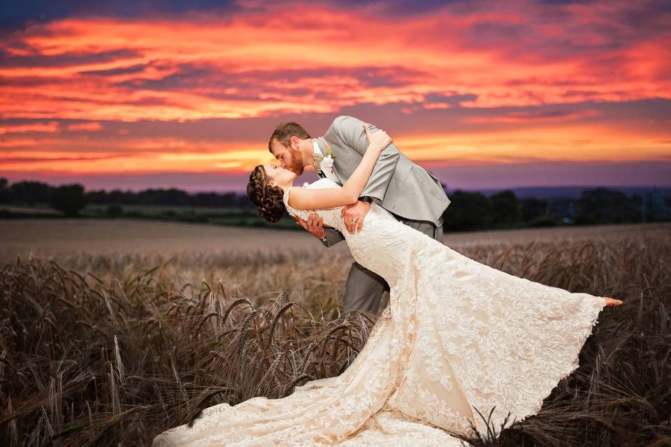 Bride and groom in a wheat field under a dramatic sky