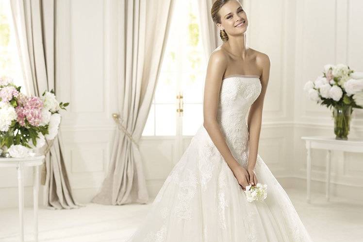 DONAIREThe Donaire wedding dress by Pronovias 2013 is ideal for a romantic day. The strapless neckline is edged with delicate tulle, a wonderful detail that accentuates the beautiful lace that decorates the bodice. This princess line wedding dress is flattering to the bride's shape, cinching the waist and smoothing the hips. The spectacular skirt has numerous layers of tulle that give it a light, flowing appearance.