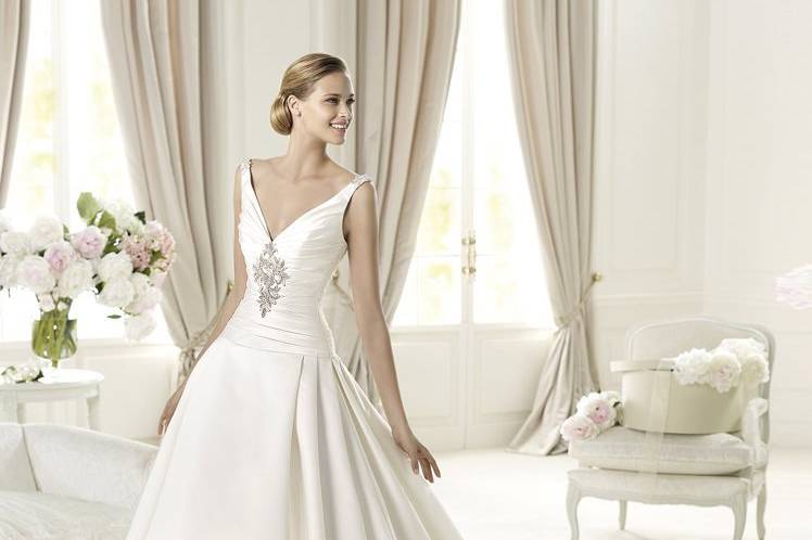 UGANDAThe romantic style of this wedding dress comes from its flattering, A-line that accentuates the bride's silhouette. Uganda from the Glamour by Pronovias 2013 collection is made of soft satin and features a flattering V-neck. Narrow straps are decorated with silver beading, which is revealed at the back. The elegant pleated skirt has a long train that gives the gown the final romantic detail.