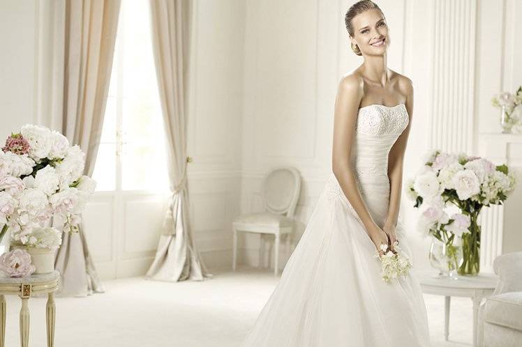 USIRIAThe romantic style of this wedding dress comes from its original draped bodice. The Ursiria model from the Glamour by Pronovias 2013 collection has a wonderful sweetheart neckline in rebrodé lace, decorated with delicate beading. The flared skirt of this dress has a flattering lace-up back. The front of the skirt has side gathers and a wonderful half-train.